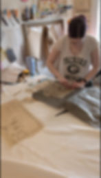 A white woman uses graphite paper and a tracing wheel to trace a pattern piece onto a white linen.
