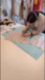 A white woman hunches over sewing pattern directions with highlighter in hand.