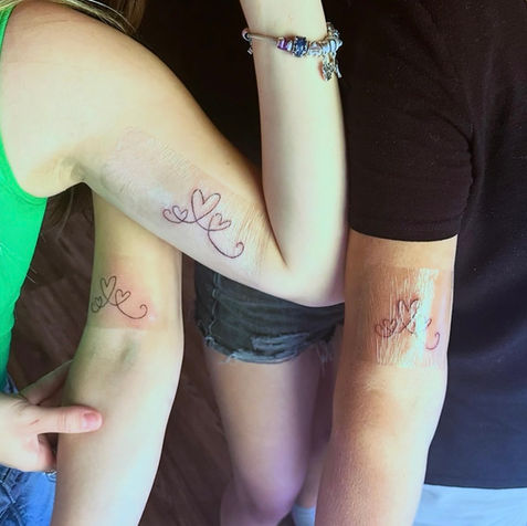 Group of three people with matching heart tattoos