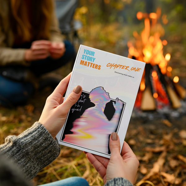 Someone holding the Your Story Matters Journal around a campfire
