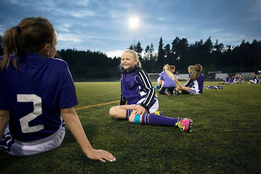 Jenter avslappende på fotballbane