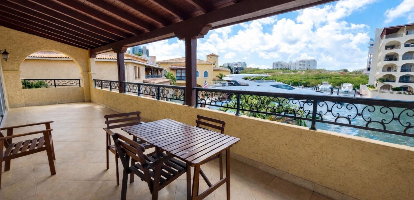 Covered terrace with outdoor dining and marina view in Sint Maarten waterfront condo for sale