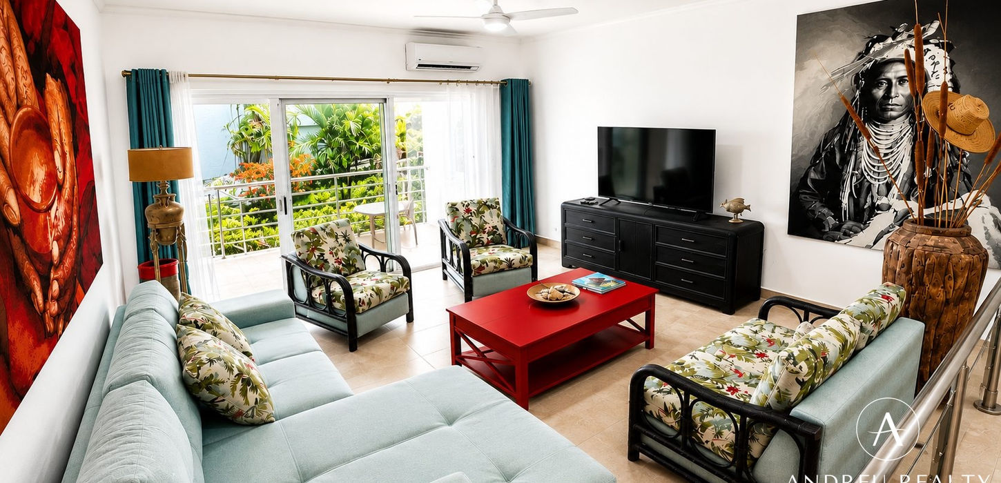 Spacious furnished living room in St. Maarten property for sale with terrace access, tropical views and air conditioning.