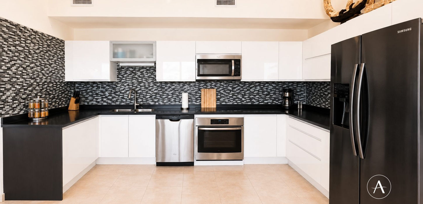 Modern white kitchen with black countertops, mosaic backsplash and stainless steel appliances in a St. Maarten condo for sale