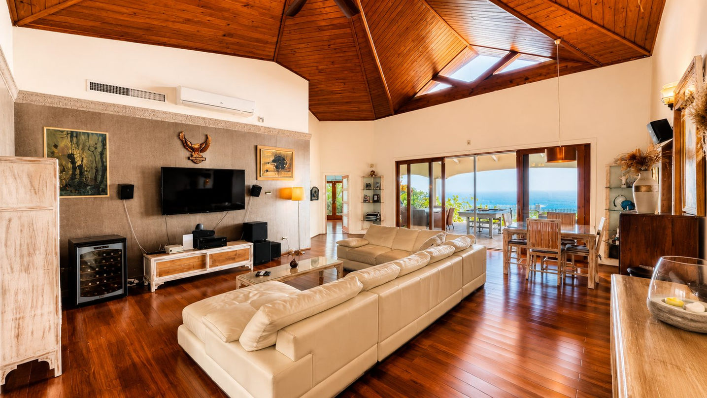 Sophisticated living area with designer furnishings, hardwood floors, vaulted ceilings, and seamless indoor-outdoor Caribbean living.