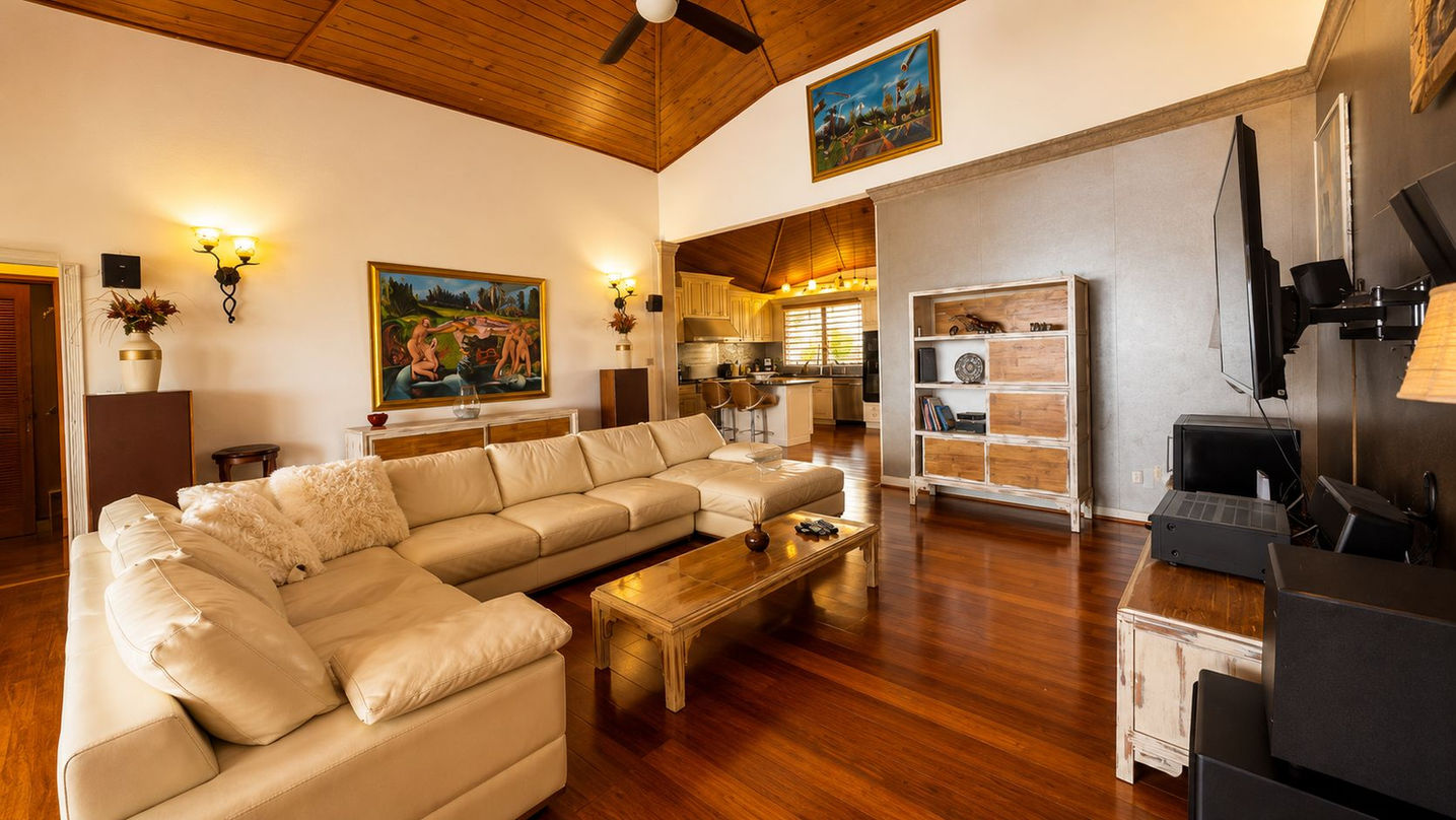 Spacious luxury lounge featuring custom furnishings, high ceilings, tropical design, and direct access to an ocean-view terrace.