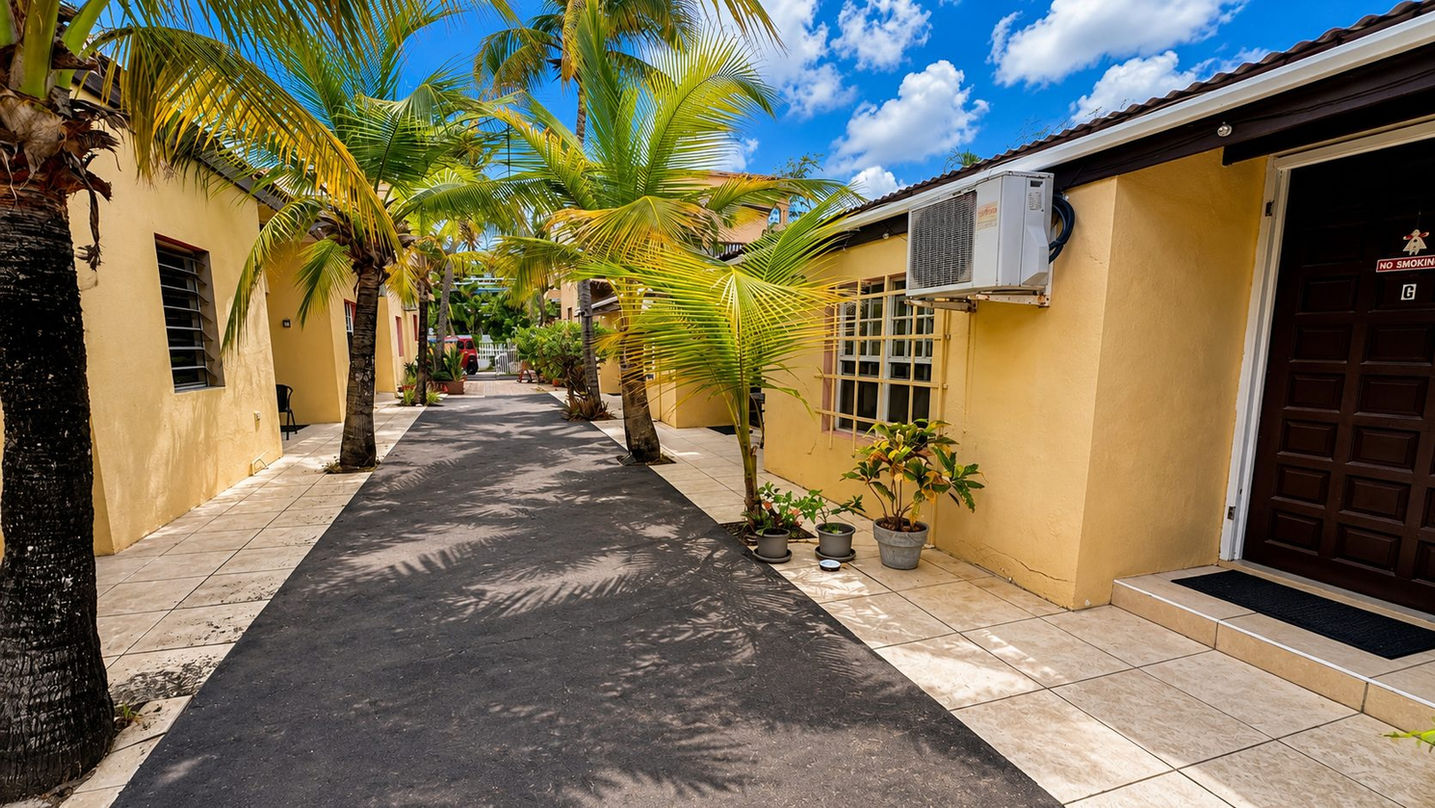 Tropical palm-lined courtyard entrance to apartment complex for sale in Beacon Hill, St. Maarten.