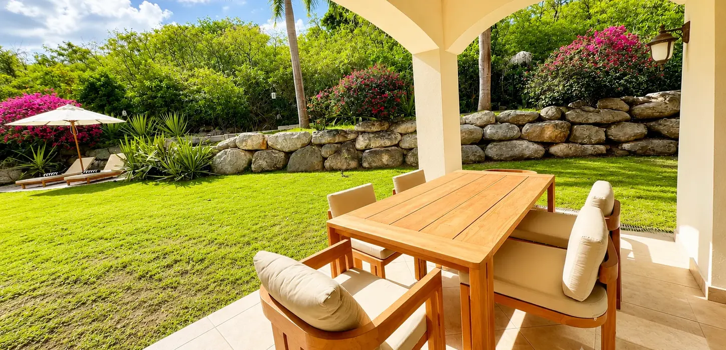 Luxury covered terrace with outdoor lounge seating overlooking a private tropical garden in St. Maarten real estate for sale.