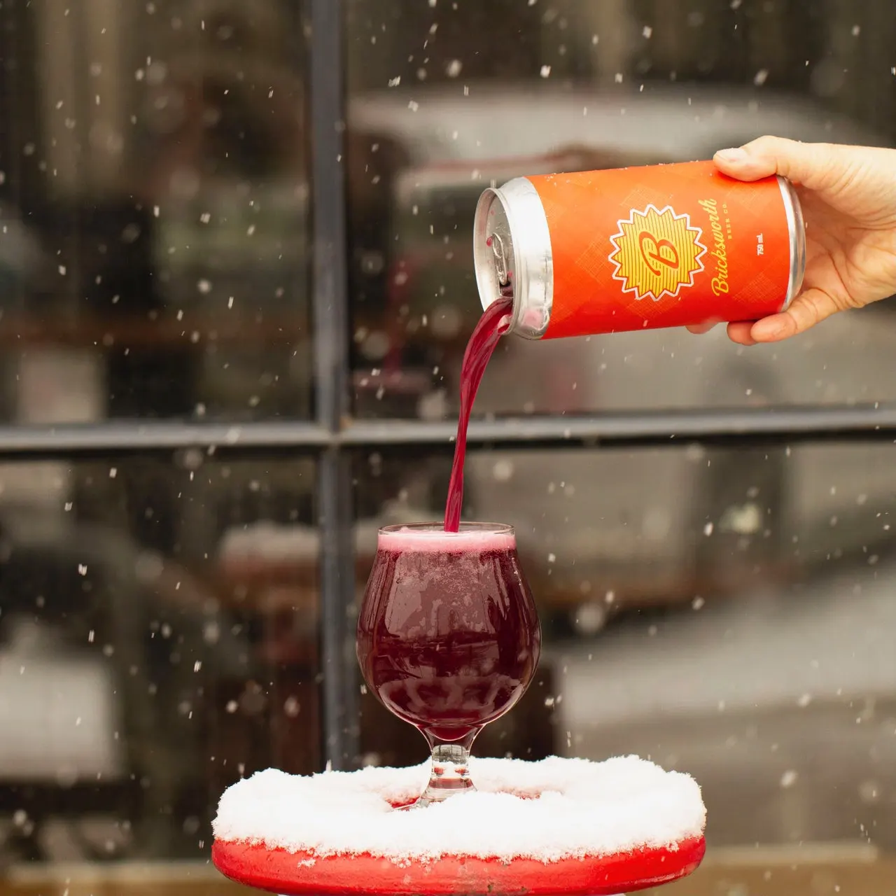 image of a deep red beer being poured into a glass in the snow