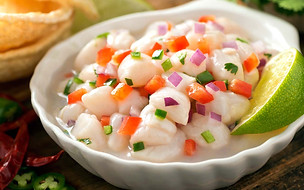 Ceviche de peixe branco com cebola roxa, pimentão e coentro, servido com limão.