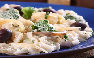 Arroz cremoso com bacalhau, preparado com Caldo Natural de legumes e finalizado com maionese, servido em um prato.