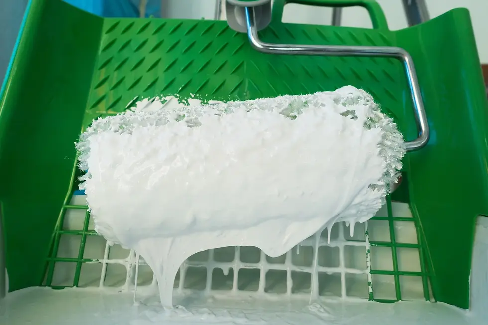 Een witte verfroller boven een groene bak waar verf in zat
