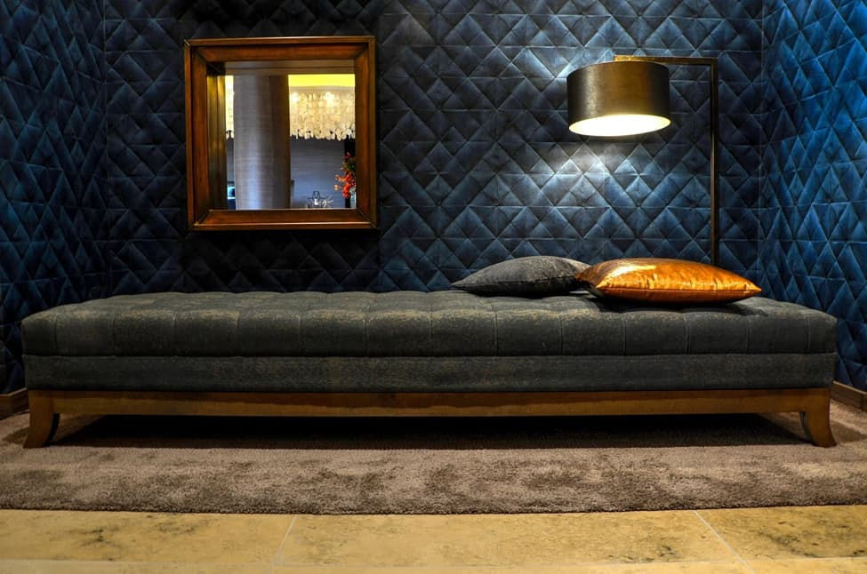 Een luxe woonkamer met een blauwe wand, er staan een grote sofa en een lamp.
