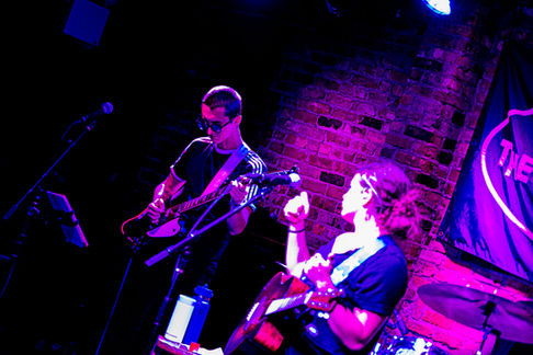 Two musicians performing on stage with guitars.