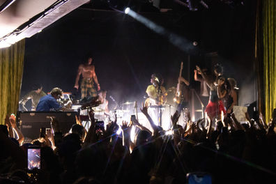 Band performing energetically on a dimly lit stage.