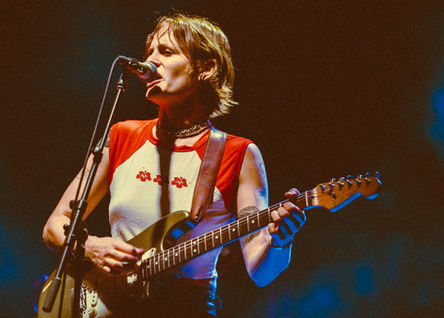 Musician playing electric guitar on stage.