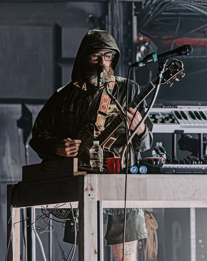 Musician performing on stage with guitar and equipment.