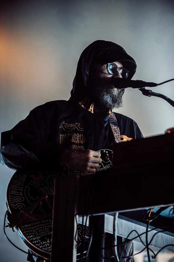 Musician performing on stage with guitar and microphone.
