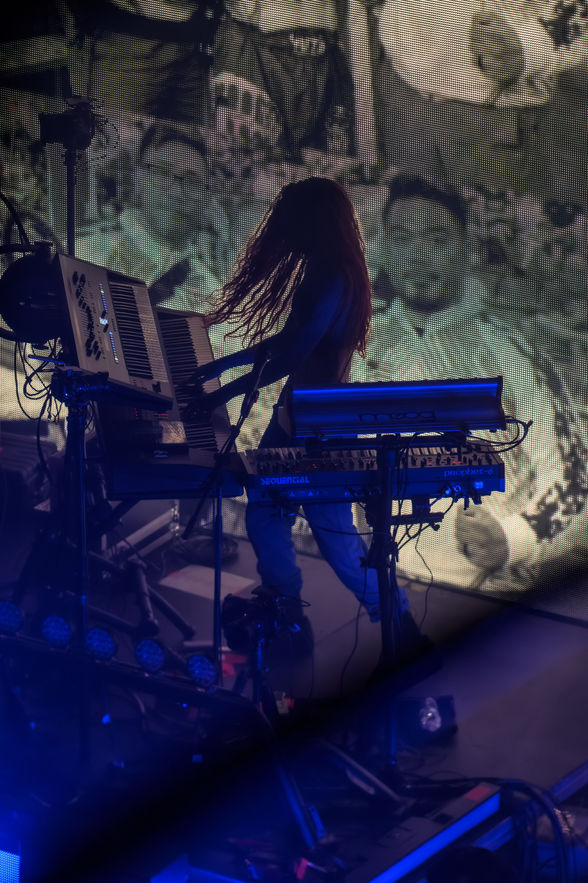 Silhouetted musician playing keyboards on stage with background.