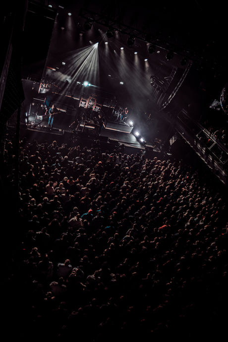 Concert crowd with stage lights in dark venue.