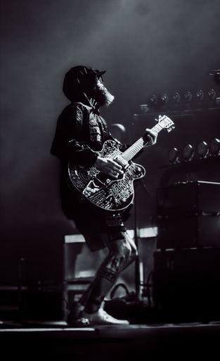 Musician playing electric guitar on stage, monochrome image.