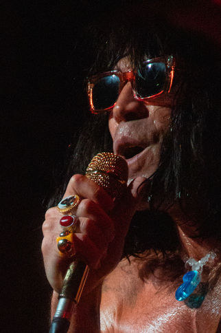Person singing passionately with microphone and sunglasses.