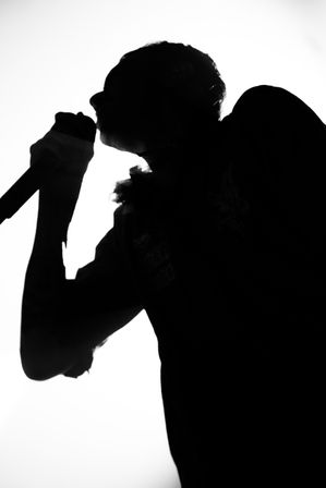 Silhouette of a person singing with a microphone.