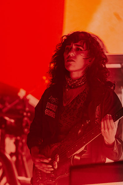 Musician playing guitar on stage with red lighting.