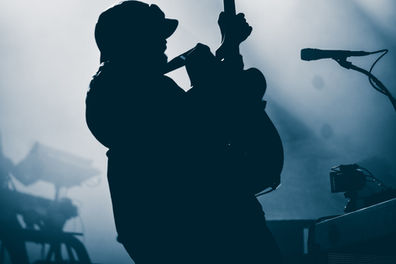 Silhouette of a person playing guitar on stage.