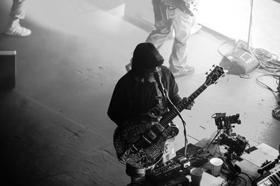 Musician playing guitar on stage, black and white photo.