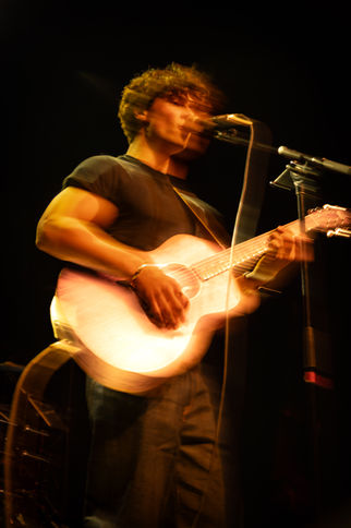 Musician playing guitar with motion blur effect.