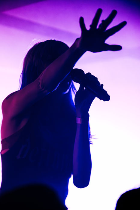 Silhouetted singer performing on stage with microphone.