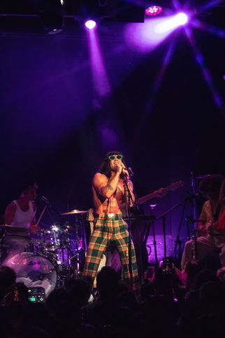 Performer singing on stage with vibrant lighting.