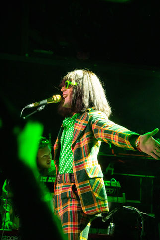Performer in colorful outfit singing on stage.