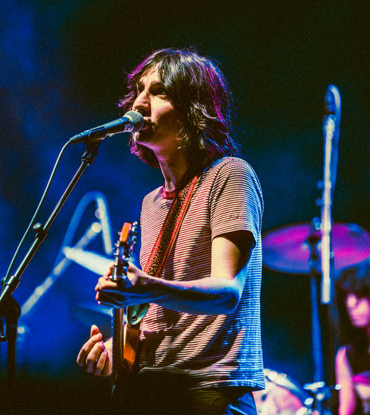 Musician performing on stage with guitar and microphone.