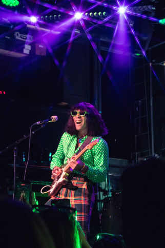 Musician performing energetically on stage with guitar.