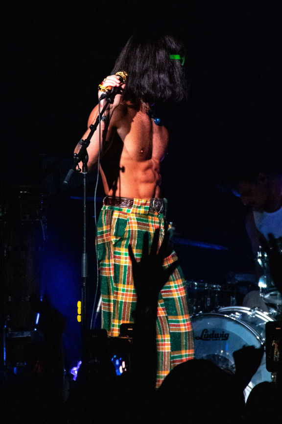 Performer in plaid pants on stage with microphone.