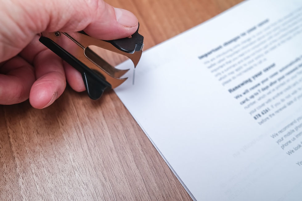 A staple remover in a person's hand over stapled papers.