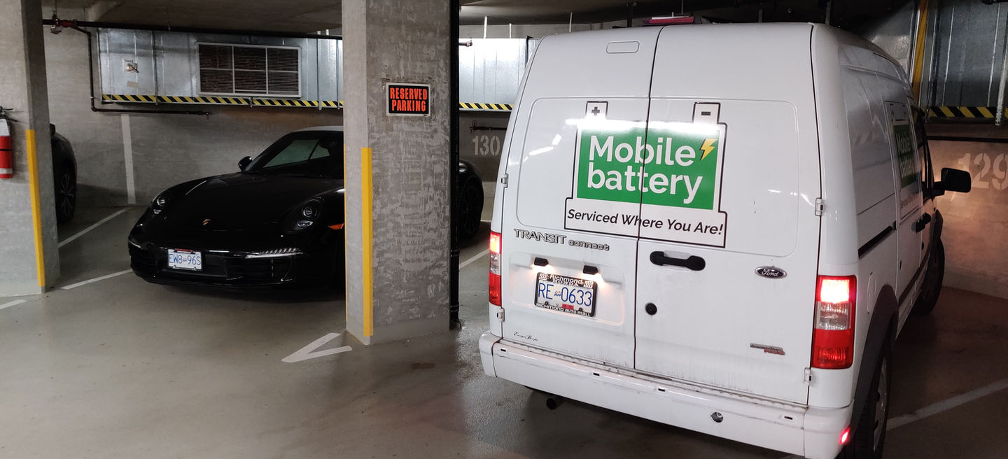 MobileBattery service van parked in a garage with a black car.
