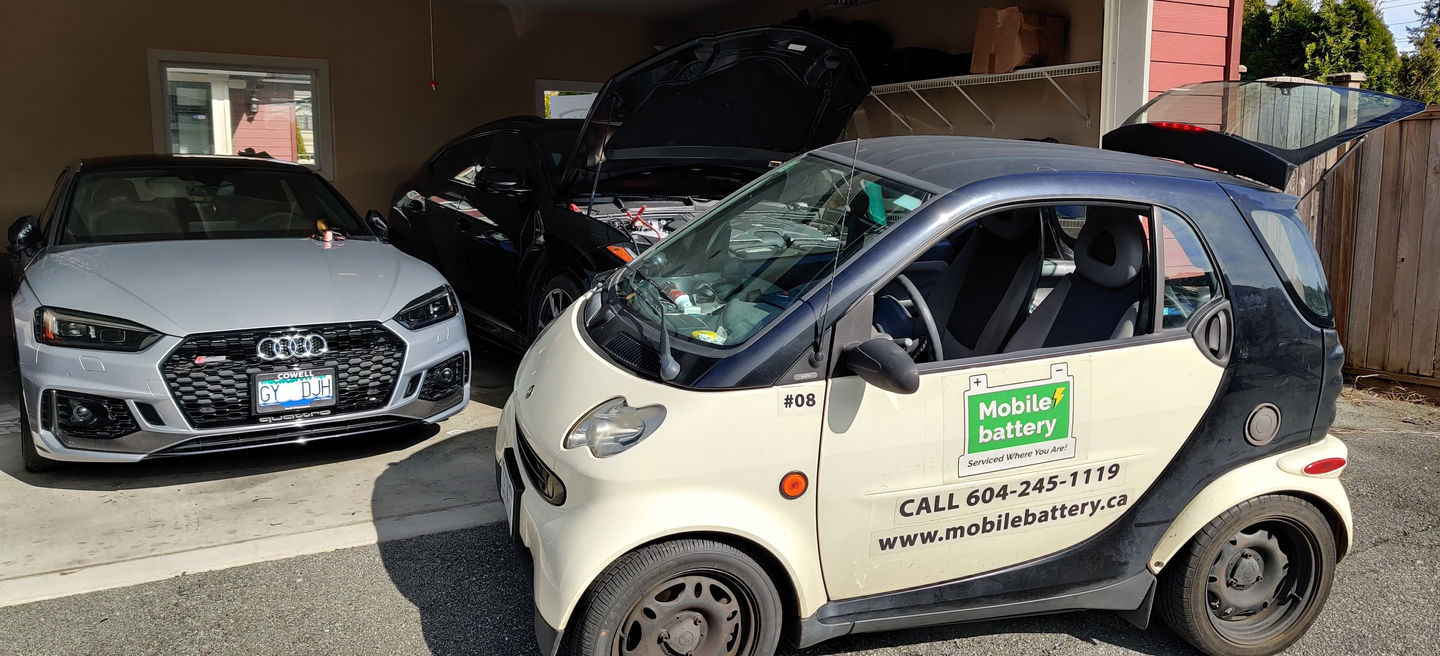 Small car with Mobile Battery logo, CALL 604-245-1119, www.mobilebattery.ca, garage setting.
