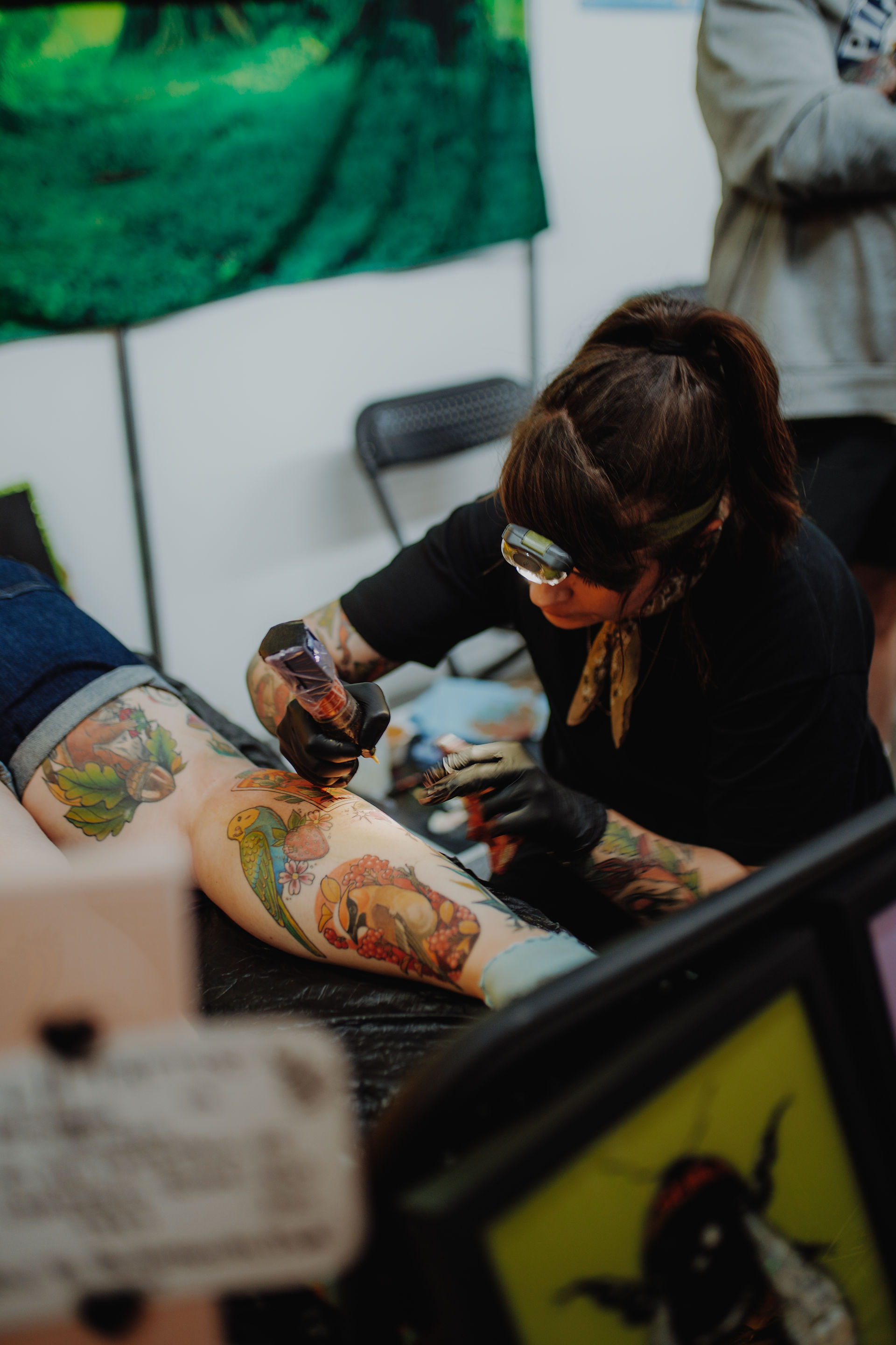 tattoo artist with a head light on tattooing a leg at a convention