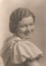 Black-and-white studio portrait of young Elsie Peterson smiling in a dress with puffed sleeves.