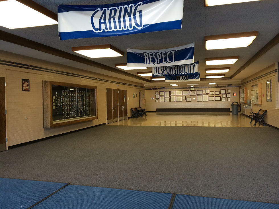 Empty Hillcrest Junior High entry hall with trophy case, benches, framed displays, and banners hangi