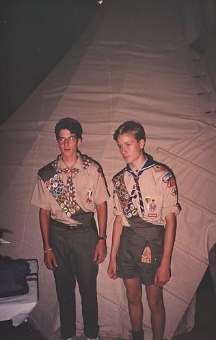 Brandon and his cousin standing in Scout uniforms in front of a large canvas tent at Camp Maple Dell.