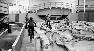 A group of riders ride across some wooden obstacles