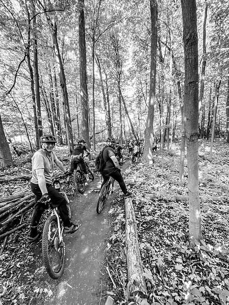 A group of mountain bikers are stopped along the side of a trail
