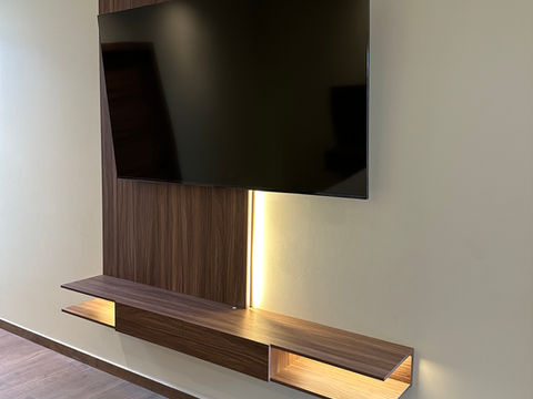 Mueble de TV flotante moderno en madera oscura con consola extendida, panel vertical y tira de iluminación LED. Diseño minimalista y elegante para sala.
