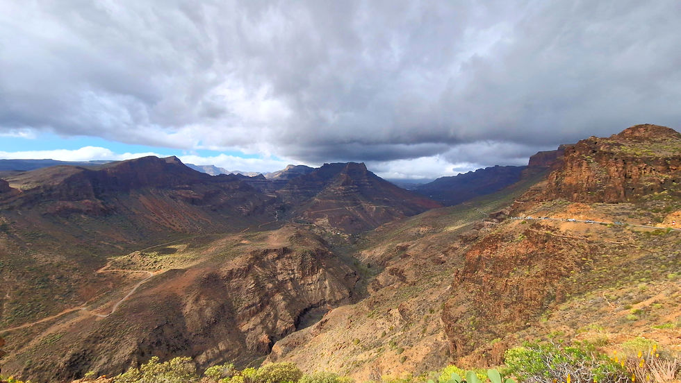 Volcanic canyon landscape on a hiking route in Gran Canaria, with rugged ridges and a blue sky.