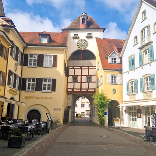 Meersburg old-town gateway and square with historic façades and café tables.