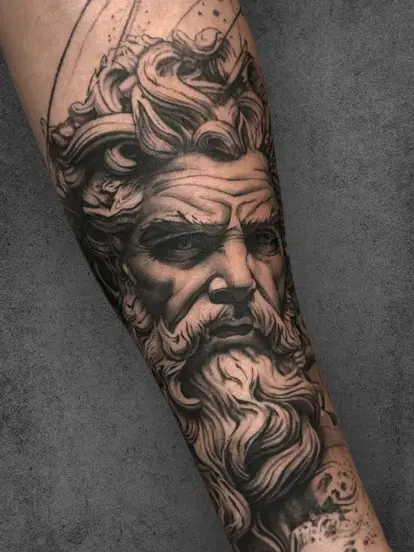 A dramatic portrait of Zeus on the forearm, emphasizing his stern expression and detailed, flowing beard.